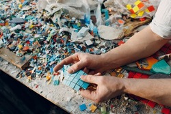 Man mosaics master chooses select smalt glass pieces for mosaic panel. Male mosaicist at work