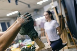 Man sculptor creates sculpt bust clay human woman model sculpture. Statue craft creation workshop studio.