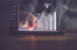 Augmented reality (AR) financial charts showing growing revenue In 2021 floating above digital screen smart phone, businesswoman having meeting about strategy for growth and success