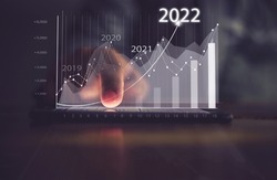 Augmented reality (AR) financial charts showing growing revenue In 2022 floating above digital screen smart phone, businesswoman having meeting about strategy for growth and success