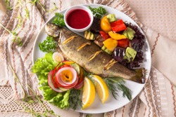 Grilled trout, carp and mullet. Juicy delicacy fish on a plate with a salad of fried vegetables. Balkan cuisine. Restaurant menu