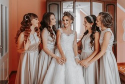 the bride's friend prepares the bride for the wedding day. The bride's friends happily pose with the bride for a photo