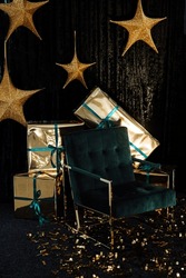 Golden stars hanging on a dark background, New Year's gifts in gold wrappers, a green chair on a dark background