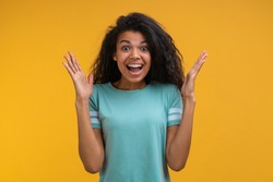 Studio portrair of cute happy joyful amazed soccer fan girl showing sincere excitement screaming yes with eyes wide open, isolated over bright colored yellow background.