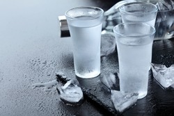 Vodka. Shots, glasses with vodka with ice .Dark stone background.Copy space .Selective focus