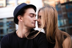 Couple dressed in black looking at each other, the guy wear black hat, a girl flying hair, close-up portrait