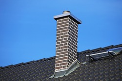 Chimney clad with clinker bricks on a newly covered roof