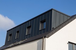 Newly tiled roof with large dormer with standing seam cladding