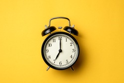 black vintage alarm clock on yellow color background