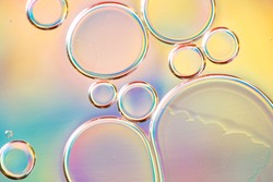 Beautiful and fantastic macro photo of water droplets in oil with a colorful background.
