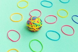 Ball or knot of thin multicolored elastic band rubbers on plain background. Tangle of thoughts.