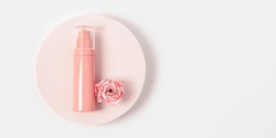 Spray for woman with essential oil rose flower on round podium on white background. Cosmetic product top view, pink pastel colored, minimal trend.