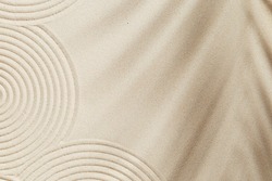 Concentration and spirituality in Japanese zen garden,  lines drawing in sand and shadows of palm leaves. Spa background, concept for meditation and relaxation. View from above.