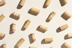 Pattern with wine corks from white and red wine on beige pastel color background with hard light and shadow at sunlight. Trend layout with bottle cap wooden cork, top view, minimal flat lay