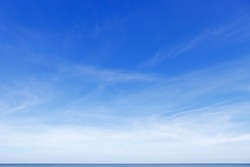 Beautiful blue sky over the sea with translucent, white, Cirrus clouds. The horizon line
