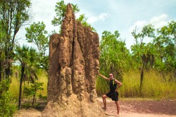 a man standing next to a giant termite mound