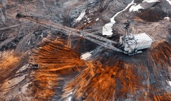 A large walking excavator works in a quarry for the extraction of rare metals. Drone view. Industrial landscape.