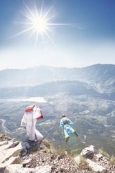 Two wingsuit pilots jumping off cliff from Monte Brento exit, Arco mountains, Italy - BASE jumping concept