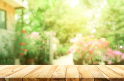Empty wood table top on blur abstract green from garden and house background. For montage product display