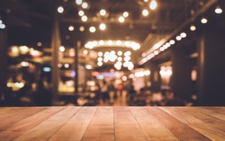 Wood table top (Bar) with blur light bokeh in dark night cafe,restaurant background .Lifestyle and celebration concepts ideas