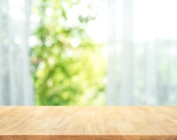 Empty of wood table top on blur of curtain with window view green from tree garden background.For montage product display or design key visual layout