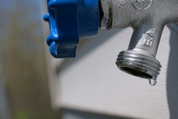 Dripping spigot outside a house on a warm sunny day