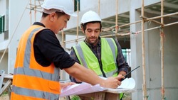Professional civil engineer foreman opening paperwork to assign responsibility to young engineer worker working with team at construction site making a check on building, Civil engineering concept