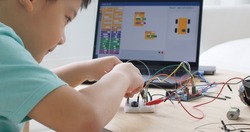 Asia home school young small kid happy smile self study online lesson excited make AI circuit toy. STEM STEAM digital scratch class on laptop screen for active children play arduino enjoy fun hobby.