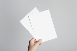A5 Flyer / Invitation Mock-Up - Male hands holding blank flyers on a gray background.