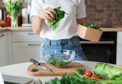 Close up woman in white t-shirt cooking salad with motion effect at home kitchen. Process of cooking healthy food, vegetable concept