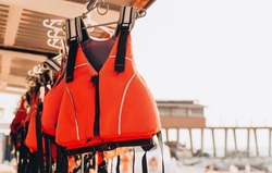 Life jacket on rail for costumer, Red Life jacket with black belts, Personal flotation device. Life jacket ready to be used by tourist going on a boat trip.