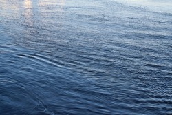 The surface of clear water in a river as an abstract background. View at blue smooth surface of the river, water surface