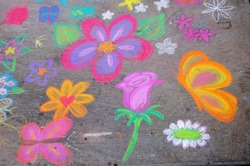 Sidewalk chalk art with childish drawings.