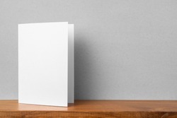 Design concept - front view of greeting card on bookshelf and grey wall for mockup, not 3D render
