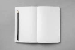 Design concept - top view of open white notebook with blank page and wooden pencil on grey background for mockup. real photo, not 3D render