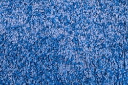 Texture of blue fabric carpet with long pile close-up. Fluffy blue frieze fur carpet texture.