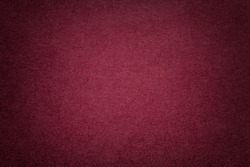 Texture of vintage dark red paper background with vignette. Structure of dense maroon kraft cardboard with frame. Felt wine gradient backdrop closeup.