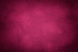 Dark purple matte background of suede fabric, closeup. Velvet texture of seamless wine leather. Felt material macro with vignette.