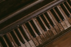 An old worn out piano. Old key board. Ancient piano background. Vintage image of the piano. 