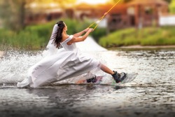 A young girl in a wedding dress riding on a wakeboard on the lake. Extreme bride. Unusual bride. An extraordinary bride.