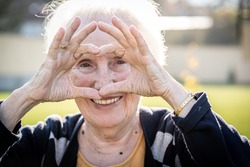 Elderly woman making heart shape with hands
