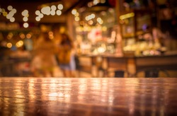 Real wood table with light reflection on scene at restaurant, pub or bar at night. Blurred background for product display or montage your products with several concept idea and any occasion.