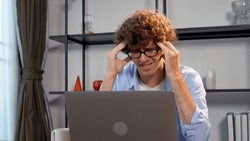 Tired unhappy young man wear eye glasses looking laptop headache depression worried problem  business online at home. Frightened businessman despair problems work loss job stress look at computer. 