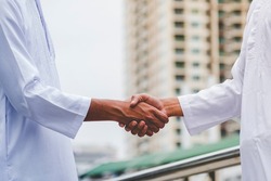 Arab Businessman Muslim dress shaking hands together. Muslim Men Teamwork business partner handshake with business Partnership. Close up hand UAE diversity multiracial people trust honesty commitment