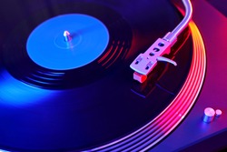 Turntable vinyl record player. Sound technology for DJ to mix & play music. Vintage vinyl record player on a background decorations for a party, bright disco lights. Needle on a vinyl record   