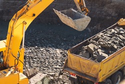 A large yellow excavator digs a foundation pit for the construction of a large residential complex. The bucket heats the ground. Building massive machinery. The initial stage of the new construction 