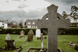 Shallow focus of a granite constructed religious cross marking an ancient grave in a typical English cemetery.
