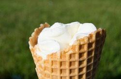 Ice cream in waffle cone on blurred grass background
