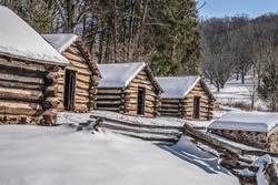 Snow coveres log cabins at Valley Forge National Park in Pennsylvania