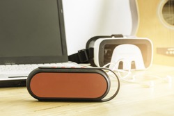 mini bluetooth loudspeaker,laptop on wooden table and blur guitar background for entertainment
